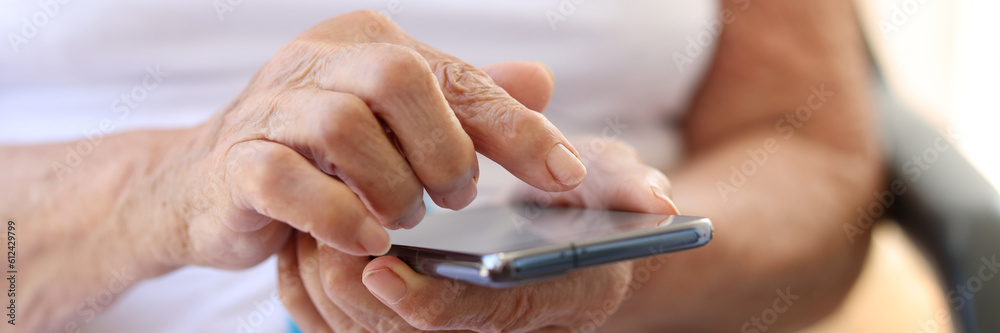 Old grandmother holding modern cellphone in hands. Woman using smartphone
