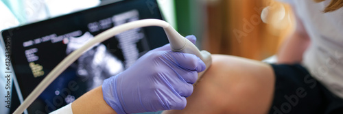 Specialist making ultrasound diagnostics of knee joint of little child