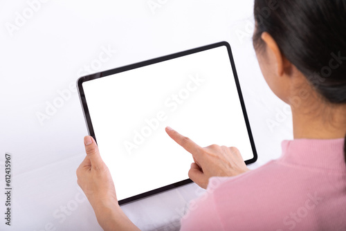 Women useing finger to touch tablet on table, tablet have white screen, rear. view from back to front of women