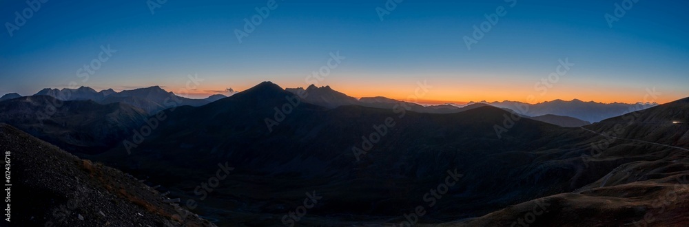 Panoramic shot of the rocky mountains during scenic orange sunset in the blue sky
