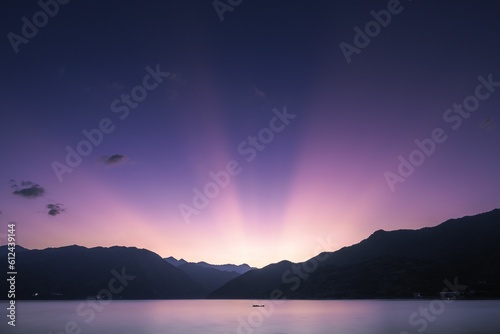 Fototapeta Naklejka Na Ścianę i Meble -  Scenery of sunlight and purple sunset sky behind mountains