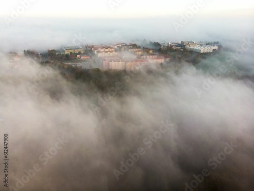 Drone shot of residential buildings on a high rocky hill covered with clouds and mist