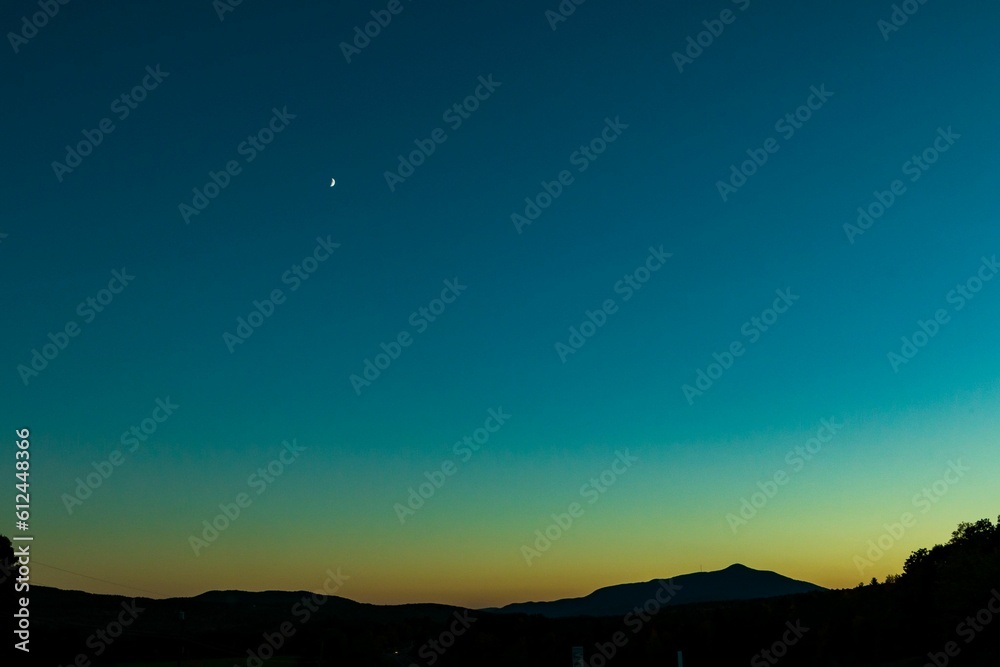 Beautiful landscape of the late sunset over the mountains with the moon just shinning