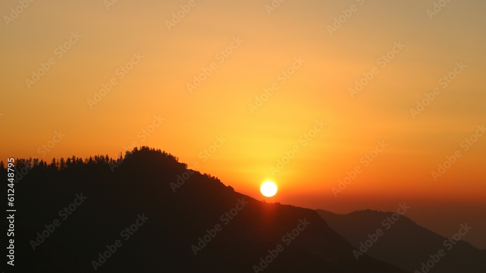 Beautiful sunset in front of the mountains with an orange sky in the background