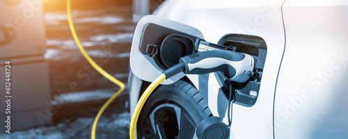 Close-up modern electric plug-in hybrid car parked near fast charger charging station point in center street old European city. Eco friendly green energy vehicle. Zero emission transport technology