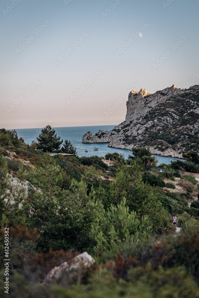 Vertical sunset view of the Massif des Calanques with the sea and the moon in the background