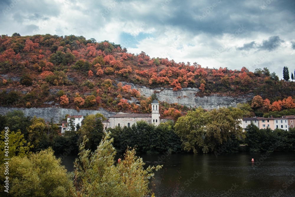 Beautiful view of a church in front of a lake surrounded by trees in autumn.