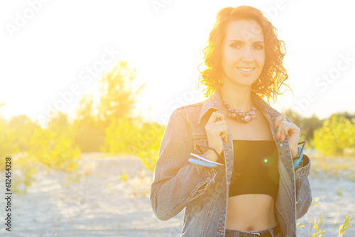 Portrait of a pretty young woman with red hair in a cotton jacket standing at sunset.