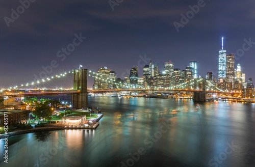 Scenic shot of the city of New York and Brooklyn bridge at night with bright beautiful city lights © Marcel Kerdijk/Wirestock Creators