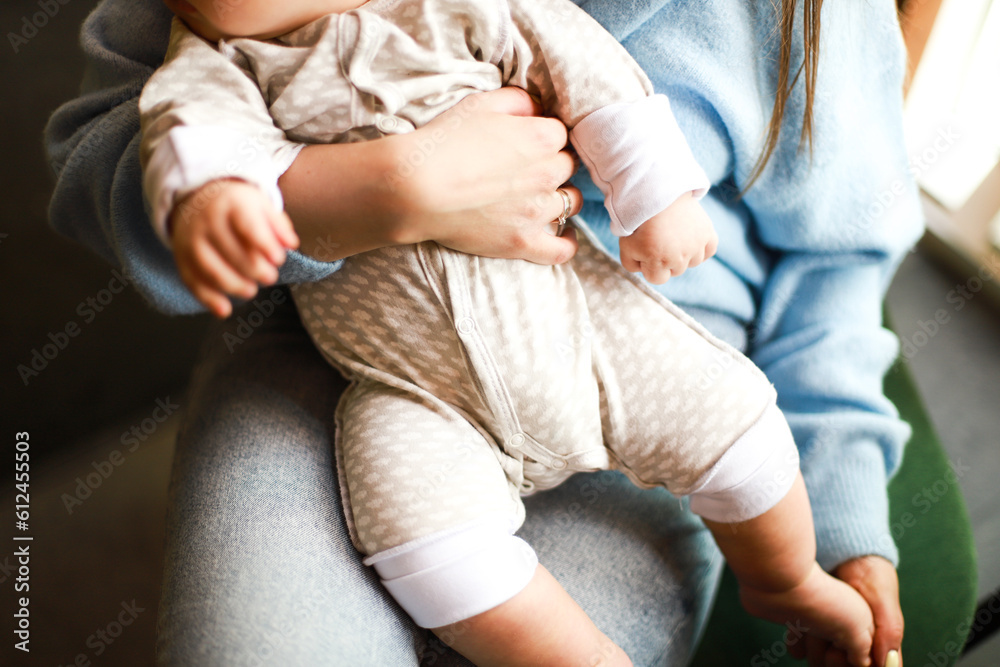 Mom is holding a baby in her arms. Baby in cotton overalls Mom is holding a baby in her arms. Baby in cotton overalls