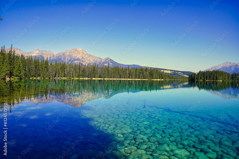 Glassy, transparent blue waters of Lake Beauvert near Jasper in the Canada Rockies