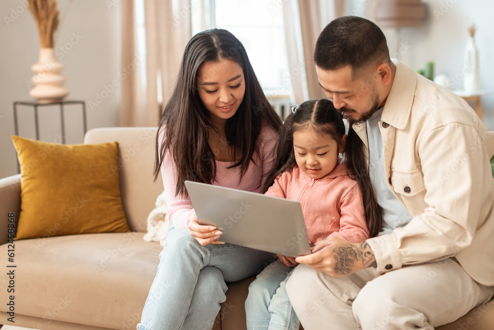 Cheerful Chinese Family Of Three Using Laptop Computer At Home Cheerful Chinese Family Of Three Using Laptop Computer At Home