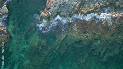 Aerial shot of the rocky mountains on the shore and a crystal clear sea, Malta, Imgiebah Bay photo