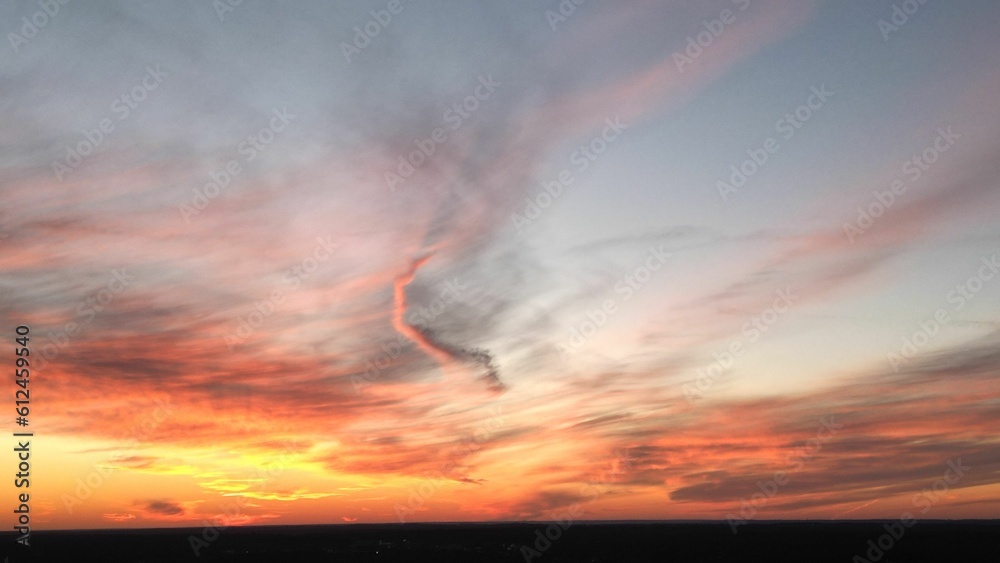 Fototapeta premium View of the orange-shaded sunset sky with cirrus clouds