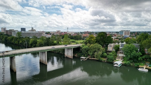 Drone view of vehicles driving along the bridge connecting the riverbank on a cloudy day