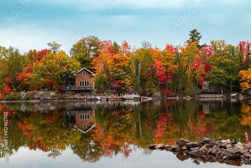 Reflection of a leafy forest in fall colors, autumn foliage and a wooden house on a mirror lake