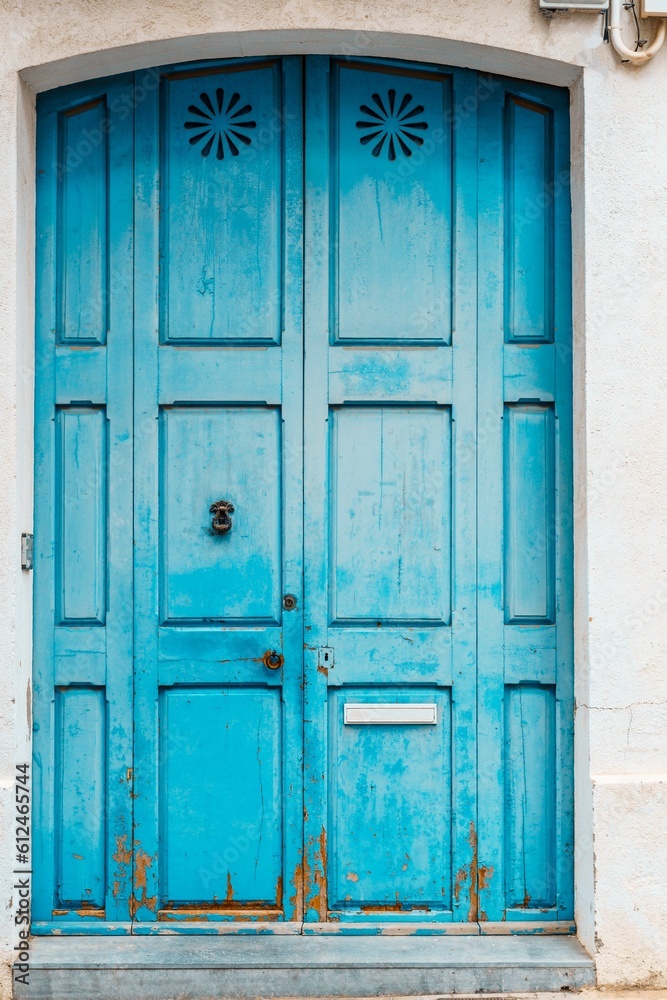 Old turquoise blue house with closed wooden entrance door.