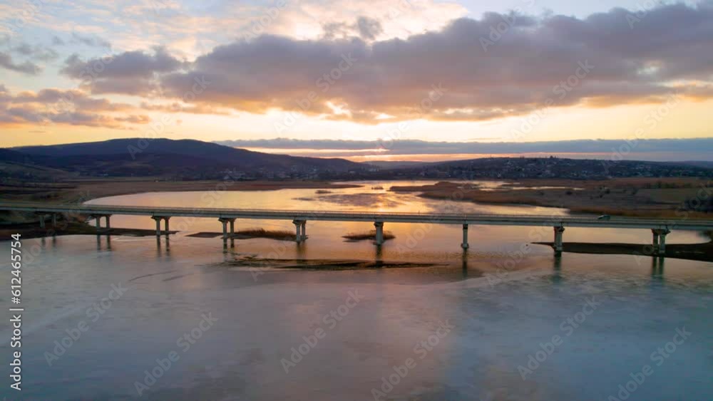 Aerial view of a bridge over a lake at sunset with a cloudy sky in the background Aerial view of a bridge over a lake at sunset with a cloudy sky in the background