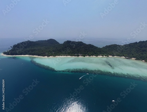 Aerial shot of Ko Kradan island in Thailand with forests and turquoise ocean around against blue sky photo