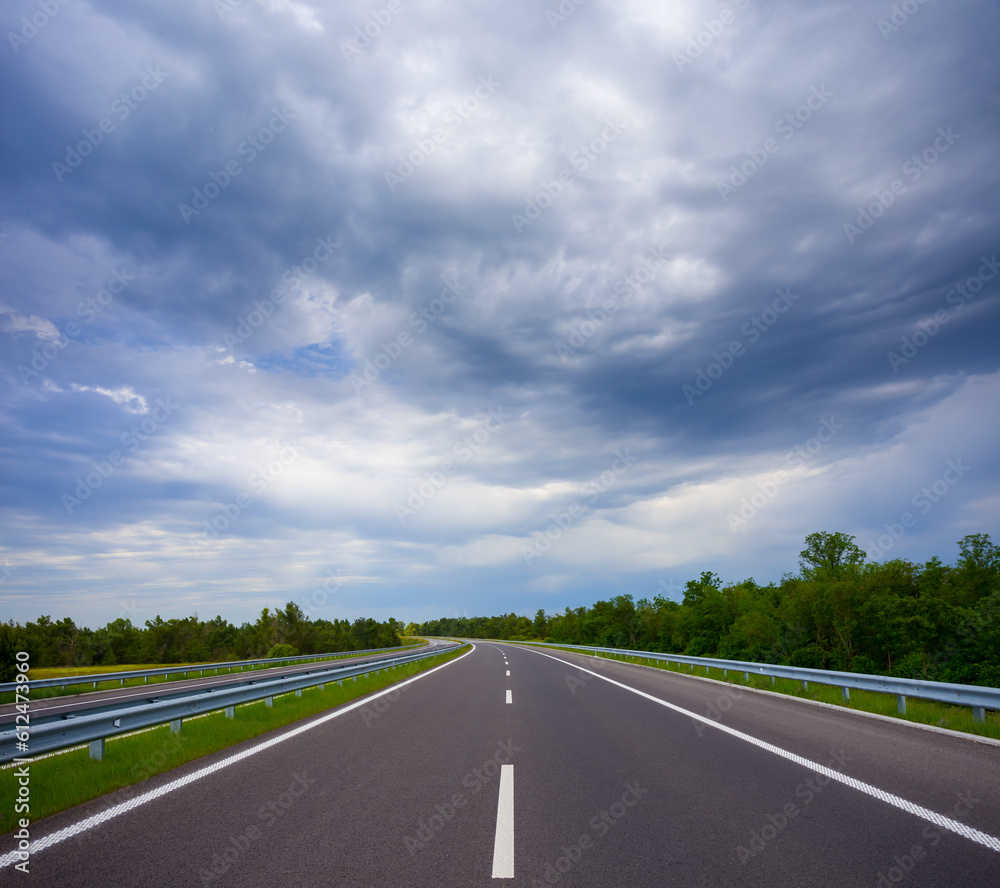 Fototapeta premium long asphalt road under dense cloudy sky