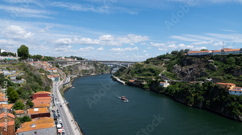 Panoramic view of the old town of Porto and the Douro river with a yacht passing through the bridge, Portugal.