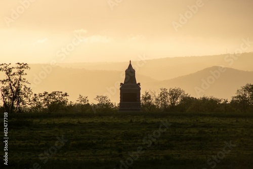 Scenic view of a statue in an open field with a majestic sunset in the background