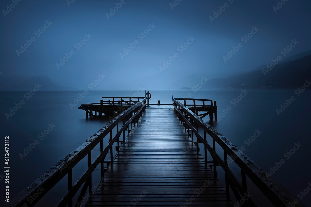 Beautiful shot of a pier on the sea with a misty sky in the background