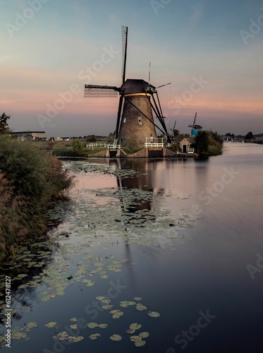 Vertical shot of a river with watermills in the background under cloudy sky at sunrise in Kinderdjik photo