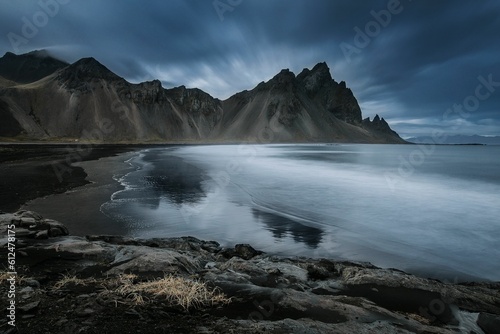 Beautiful scenery of the water in Stokksnes beach with Vestrahorn Mountains and cloudy sky, Iceland © Elin Iversen/Wirestock Creators