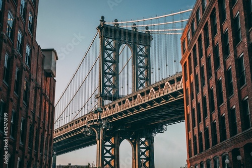 Fototapeta Naklejka Na Ścianę i Meble -  Famous Brooklyn Bridge between two buildings against the blue sky
