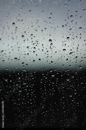 Vertical shot of rain droplets on a glass surface