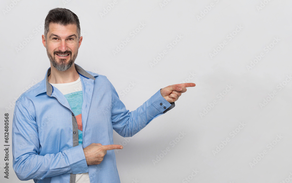 Portrait of smiling charming young adult businessman wearing blue shirt pointing away at copy space isolated on gray background Portrait of smiling charming young adult businessman wearing blue shirt pointing away at copy space isolated on gray background