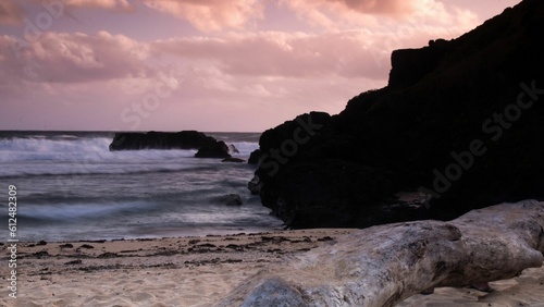 Closeup shot of a rocky coast and turbulent sea waves during a warm sunset