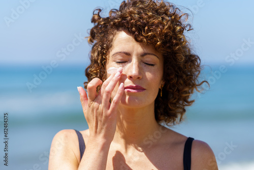 Sensual woman applying sunscreen on face
