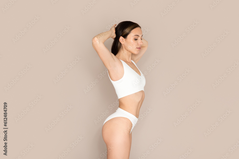 Obraz premium Well-fit beautiful young woman posing in underwear on beige