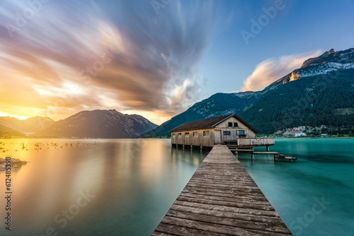 Scenic view of a sunset sky over the wooden pier to the house in a water of sea