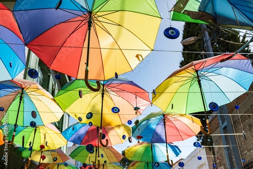 Low-angle shot of colorful umbrellas and Nazar amulets hanging in the street