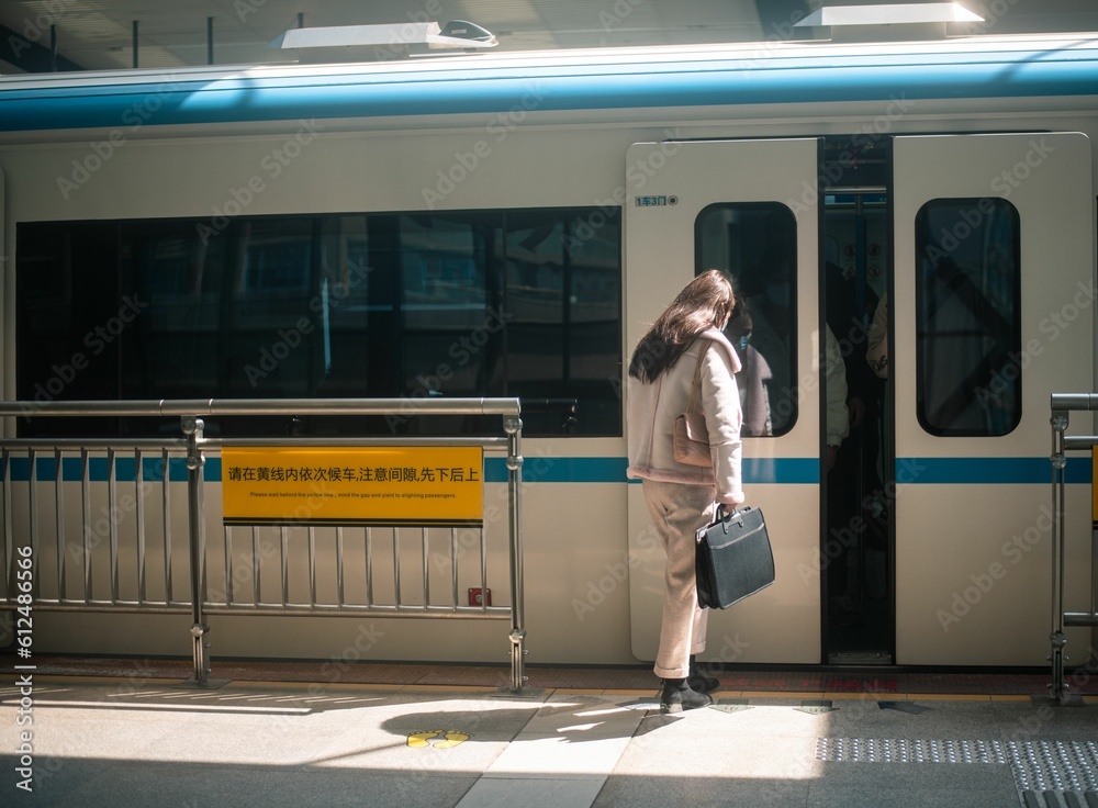Female passenger on a station platform entring a train in China