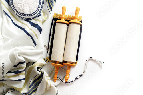 Torah scroll with a pointer, prayer shawl tallit and kippah on a light background
