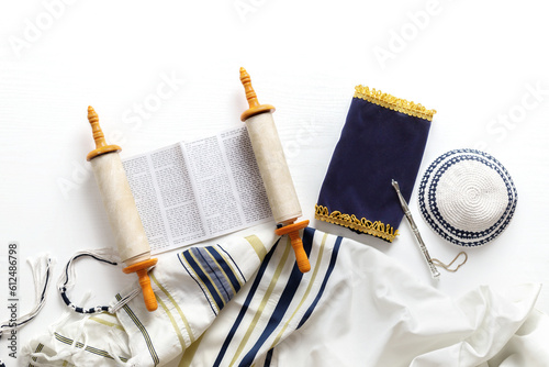 Torah scroll with a pointer, prayer shawl tallit and kippah on a light background photo