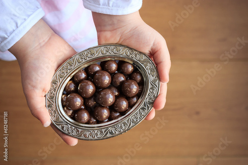 Chocolates in silver bowl on the little girl hands. Traditional ramadan and sacrifice holiday in Turkey. Turkish culture concept.