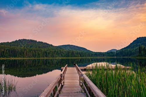 Tranquil scenery of colorful sunset over the forested mountains and a lake