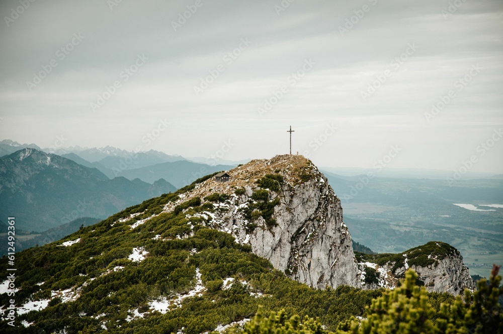 Rocky summit in the Alps with a cross on top on a sunny day