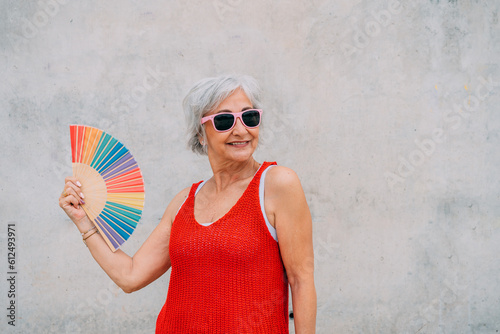 Wallpaper Mural Cheerful elderly woman using rainbow hand fan on street Torontodigital.ca