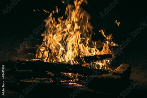 Closeup of a beautiful fire outside with logs burning inside its orange flames at night