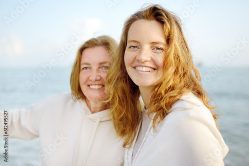Redhead senior mother and her beautiful adult daughter are walking together and laughing