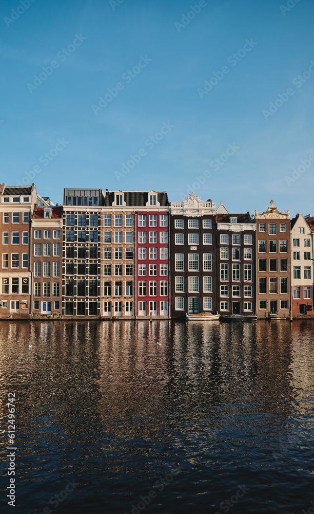 Vertical shot of colorful houses on the shore of a canal in Amsterdam, the Netherlands