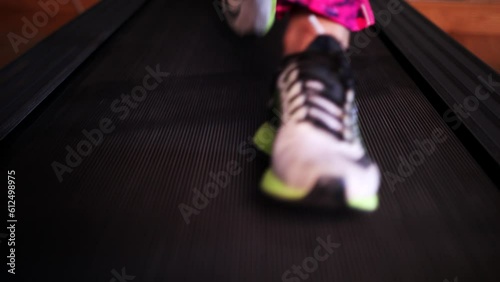 High angle slow motion closeup of a feet in sneaker running on a treadmill photo