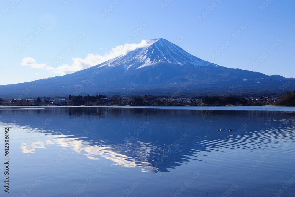 Landscape view of the snow-covered mountain reflected in the water against a blue sky