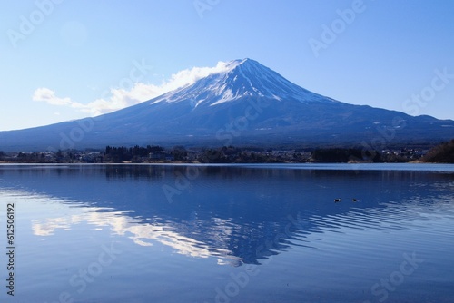 Landscape view of the snow-covered mountain reflected in the water against a blue sky